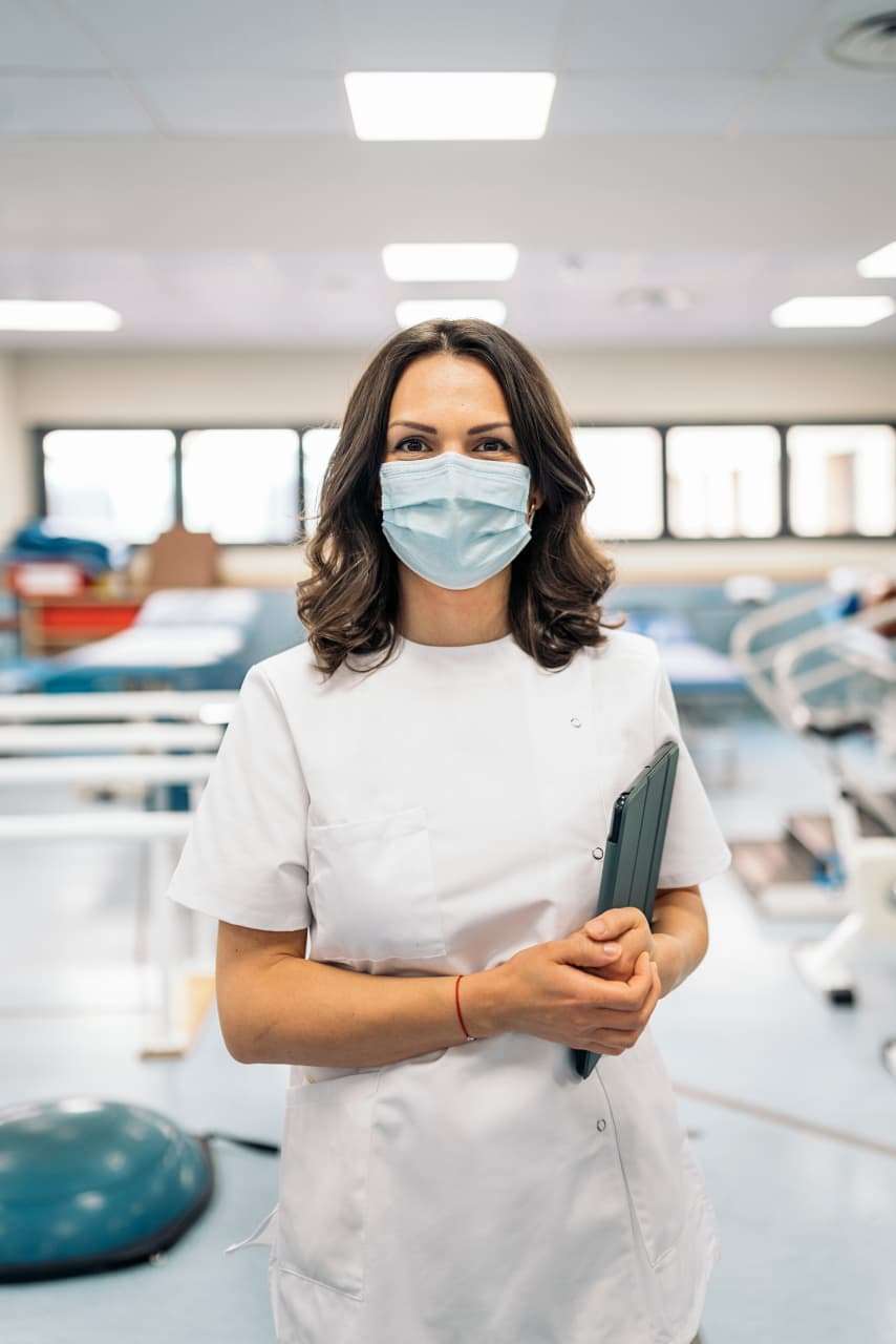 A healthcare professional in blue scrubs uses a smartphone