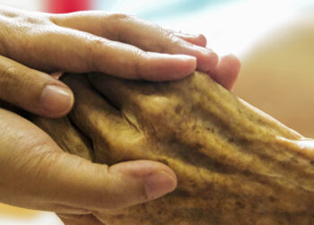 Hospice nurse holding patient's hand
