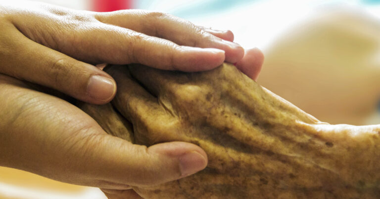 Hospice nurse holding patient's hand