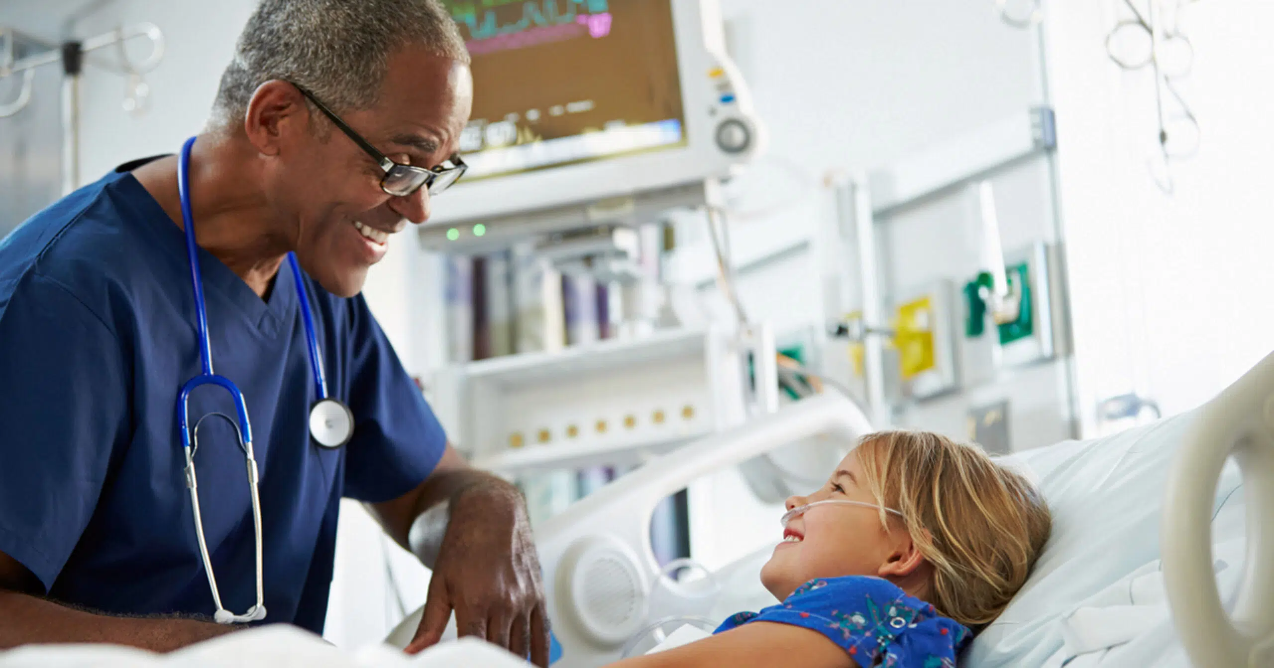 Male nurse talking to child in hospital bed
