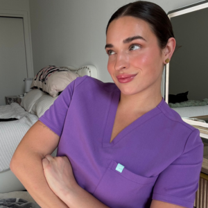 Nurse in purple scrubs smiling for a portrait.